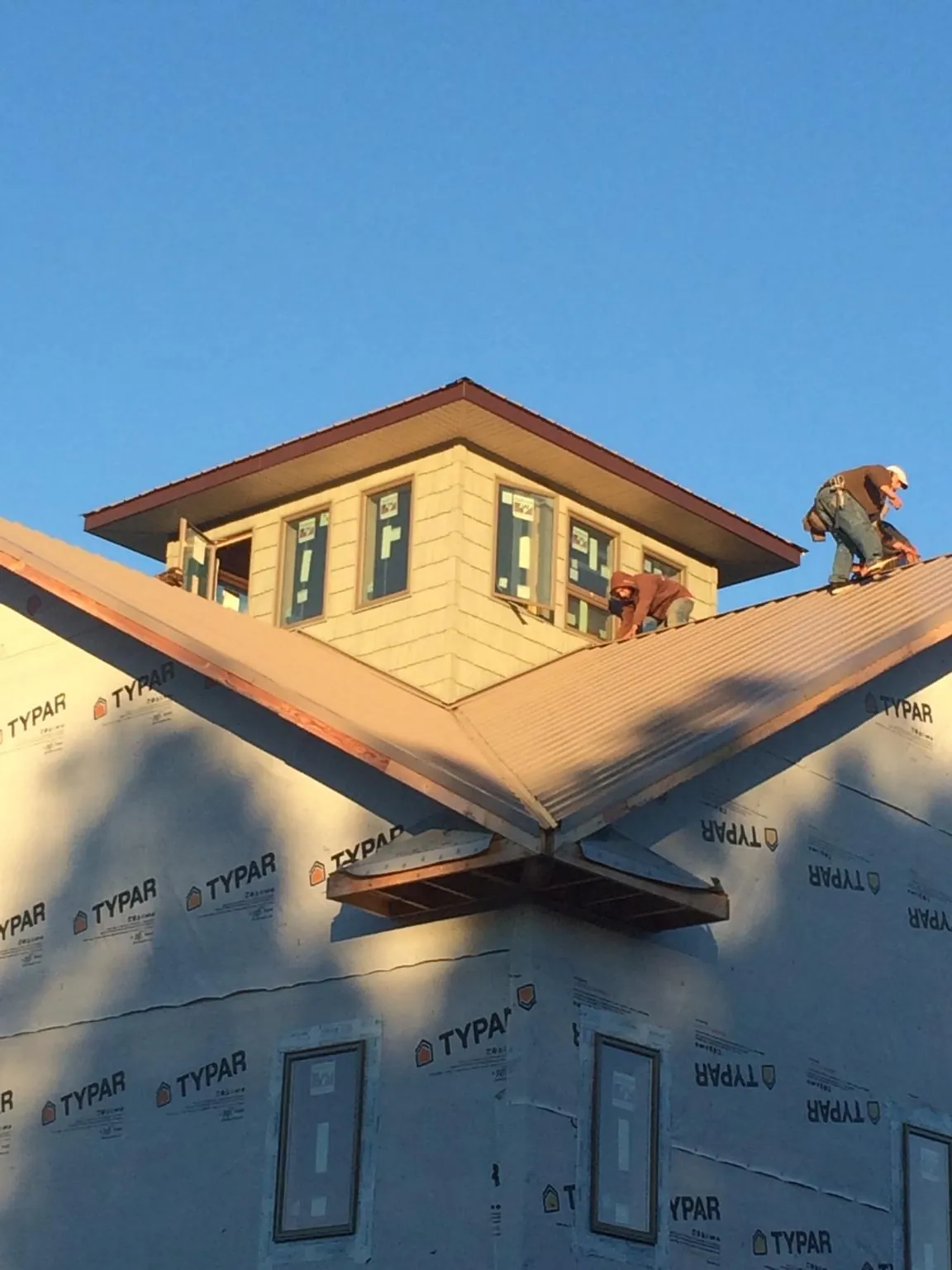 Roofers working around a rooftop cupola on a new metal roof at sunset — Roof Waterproofing in Lillian by Roofing Brothers